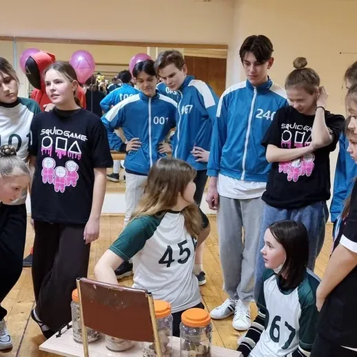 Команда молодых людей участвует в конкурсах и играх в помещении на празднике в школьном зале