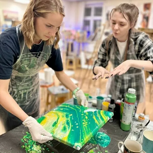 Две девушки создают абстрактную акриловую картину в художественной студии во время мастер-класса