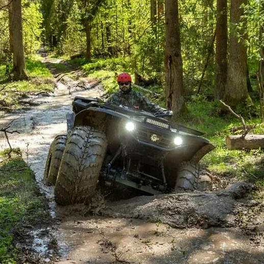 Внедорожный ATV преодолевает грязь в лесу на солнечном дне