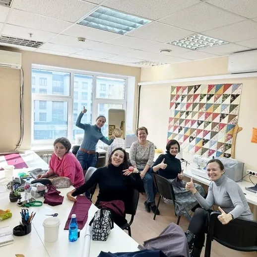 Женщины за швейными машинами в уютной мастерской по шитью в центре города