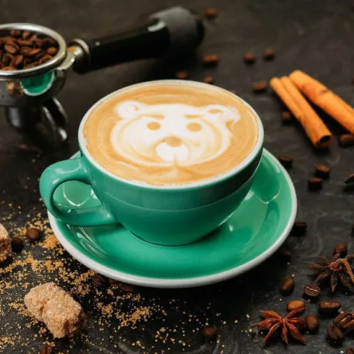 Чашка кофе с рисунком медведя в уютной обстановке с специями и сахаром