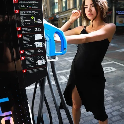 Женщина заправляет автомобиль на станции в центре города в ясный день