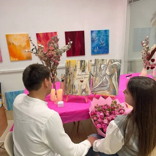 Пара наслаждается выставкой абстрактного искусства в уютной студии с цветами и картинами