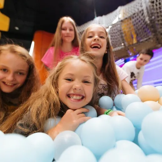 Дети играют в цветных шариках в развлекательном центре, радостно смеясь и общаясь друг с другом