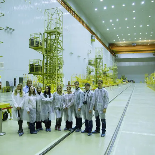 Группа специалистов на заводе, приготовляющем оборудование для космических запусков, во время экскурсии в цехе