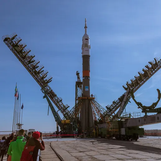 Ракета Союз готовится к запуску с космодрома Байконур в ясный день, наблюдатели собрались у стартовой площадки