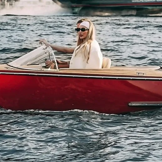 Женщина управляет красной моторной лодкой на озере в солнечный день, наслаждаясь прогулкой по воде