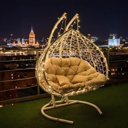 Уютное кресло-качели с огоньками на фоне ночного города и засветкой высоток