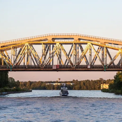 Мост над рекой в городе на закате, лодка плывет под ним