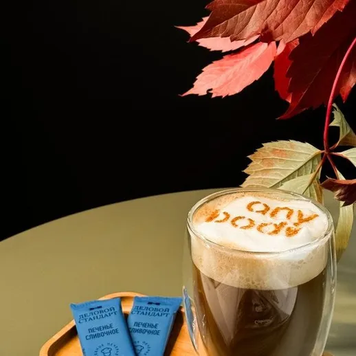 Кофе с пенкой и надписью на столе с осенними листьями и сахаром рядом в современном интерьере