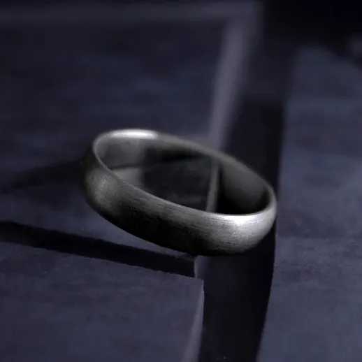 Серебряное кольцо на темной поверхности в свете утреннего солнца, создающее атмосферу уюта и тишины