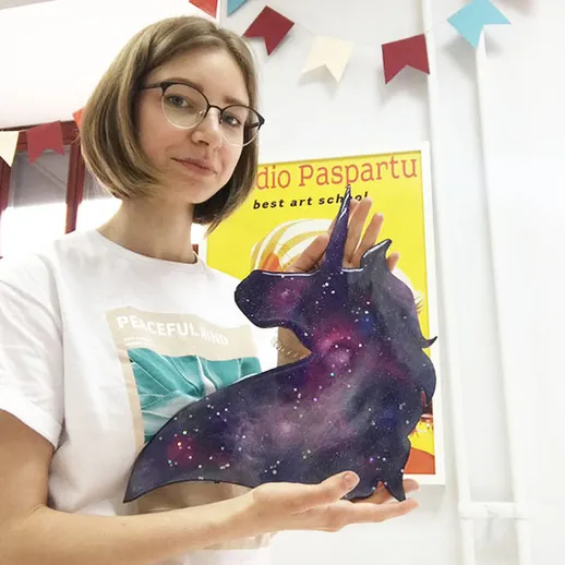 Женщина с фигуркой единорога на занятии по искусству в студии в жаркий день