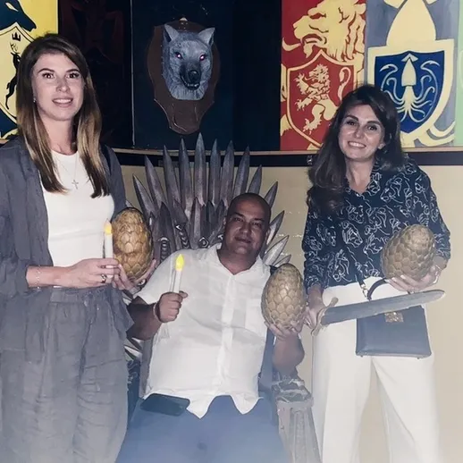 Две женщины и мужчина на троне в тематическом кафе с ананасами в руках