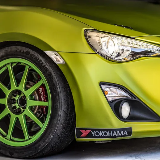 Яркий спортивный автомобиль с зеленым кузовом и дисками в гараже