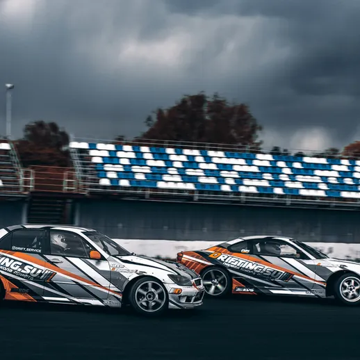 Дрифтинг автомобилей на трассе в осенний день с темными облаками