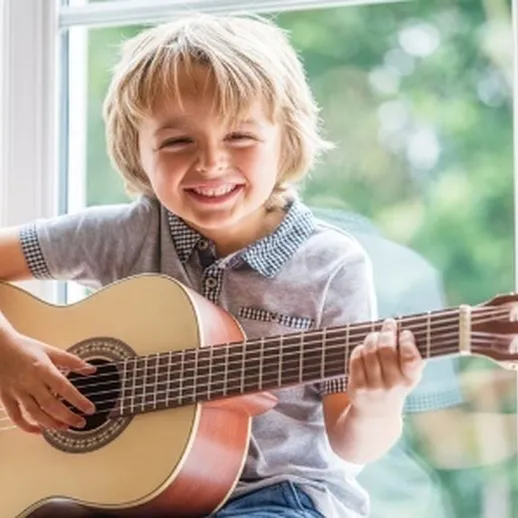 Мальчик улыбается и играет на гитаре у окна в солнечное время