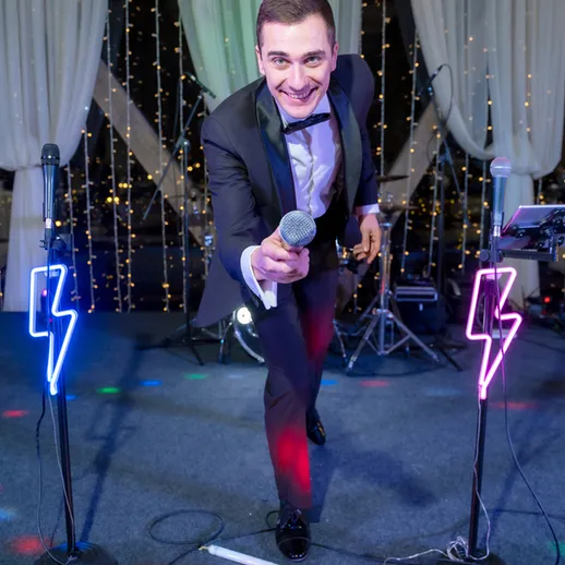 Музыкант с микрофоном на сцене, выступающий на празднике с яркими огнями