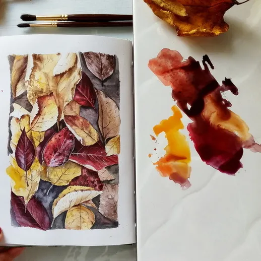 Осенняя композиция из высушенных листьев и акварельная палитра на столе художника