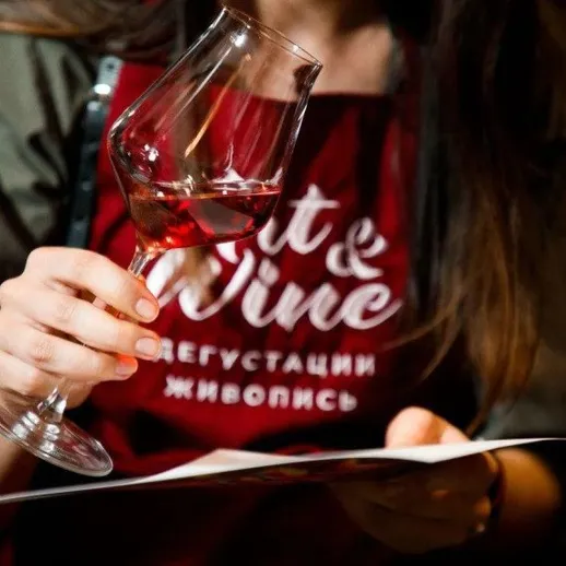 Девушка держит бокал вина и смотрит на меню в винном баре в вечернее время