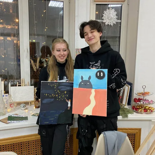 Два художника показывают свои картины в уютной студии на зимнем творческом вечере