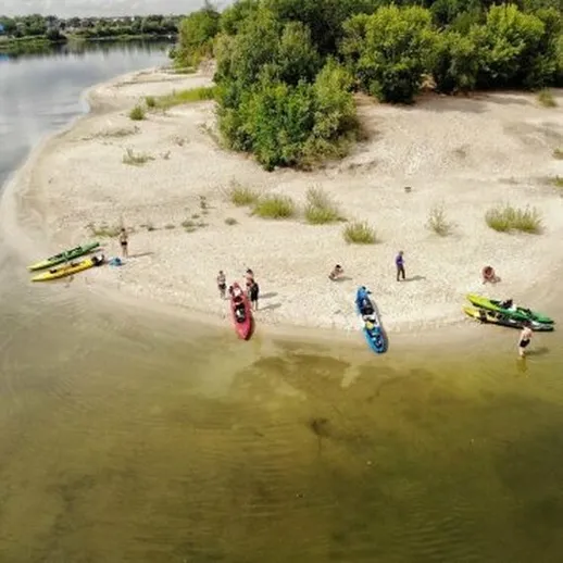 Групповая активность на пляже у реки: каякеры отдыхают на солнечном берегу в летний день