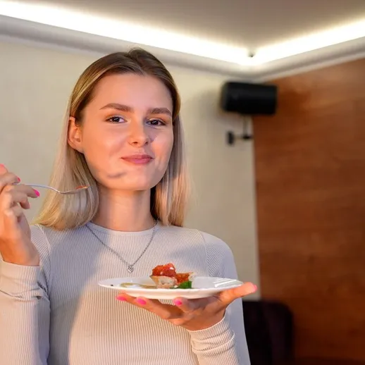 Девушка наслаждается десертом в уютной комнате, освещенной мягким светом, во время дружеской встречи