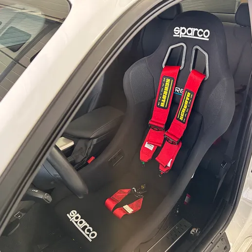 Спортивное гоночное сиденье Sparco с безопасными ремнями в автомобиле на солнечном дне