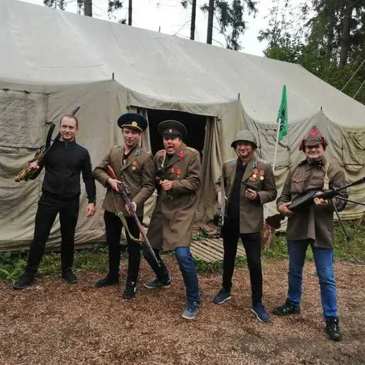 Люди в форме военных стоят рядом с палаткой в лесу с оружием в руках