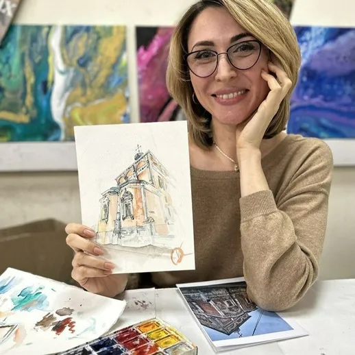 Женщина с акварельным рисунком здания в студии уютного художественного класса в Москве на протяжении зимнего дня
