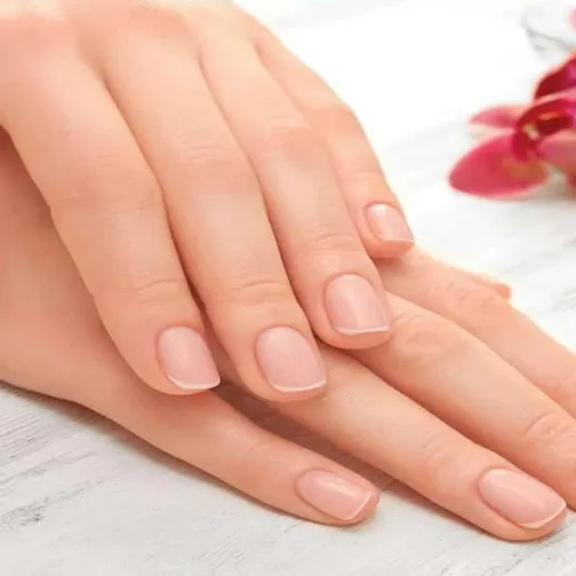 Ухоженные руки с аккуратным маникюром на светлом фоне и цветами рядом