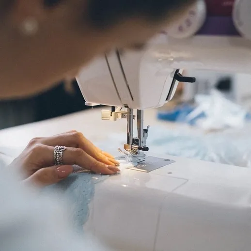 Швейная машина в работе: женщина шьёт ткань в уютной домашней обстановке в начале вечера