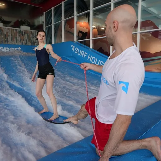 Урок серфинга для начинающих в закрытом аквапарке с тренером и учеником, который учится балансировать на доске