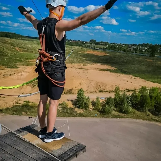 Прыжок с тарзанки на фоне зелёных холмов и голубого неба в яркий солнечный день