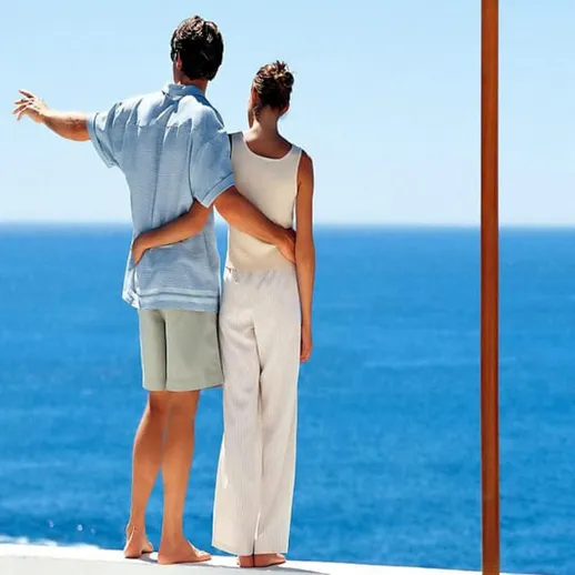 Пара любуется морем на берегу в солнечный день, наслаждаясь романтическим моментом вдали от городской суеты