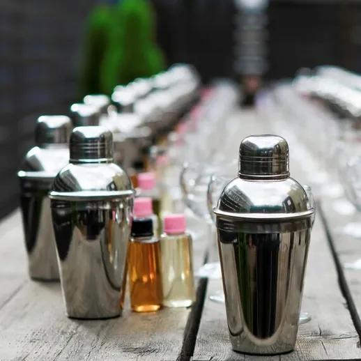 Столовая на улице с металлическими шейкерами и бутылками для коктейлей на деревянном столе