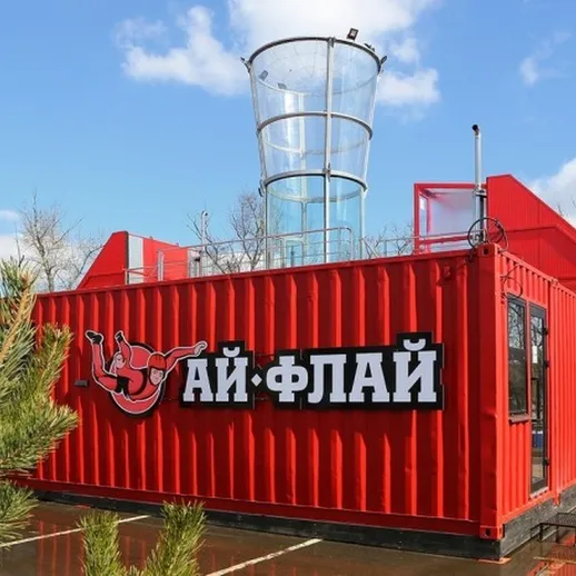 Красный контейнер с большим стеклянным элементом и логотипом на фоне чистого неба