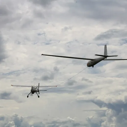 Полет самолета с буксировщиком над облачным небом в районе аэродрома