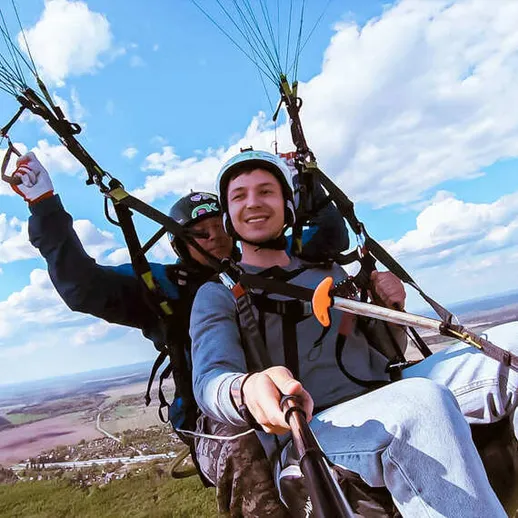 Парапланиристы наслаждаются полетом над живописным ландшафтом в ясный день