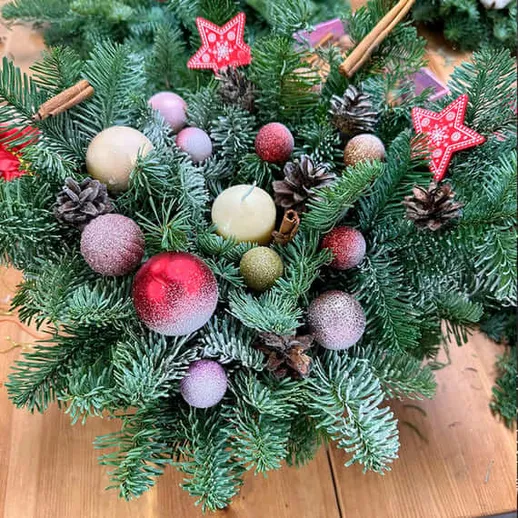 Новогодний букет из еловых веток с рождественскими украшениями на деревянной поверхности