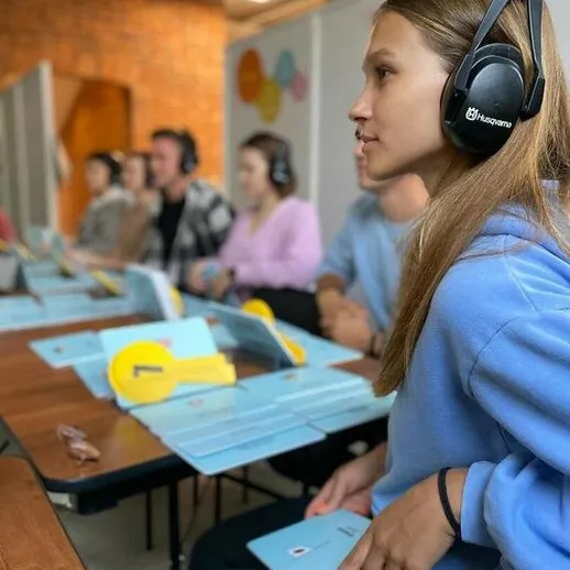 Группа людей слушает обучение в классе, используя наушники, на мероприятии в уютном помещении