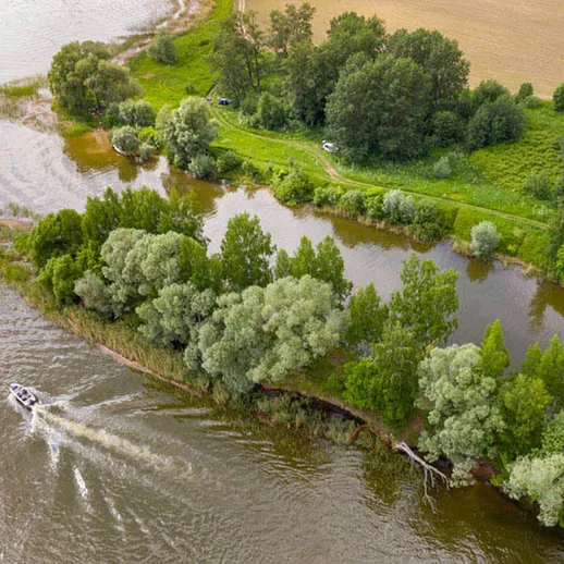 Река с зелеными берегами и моторной лодкой, плавающей вдоль живописного ландшафта в ясный день