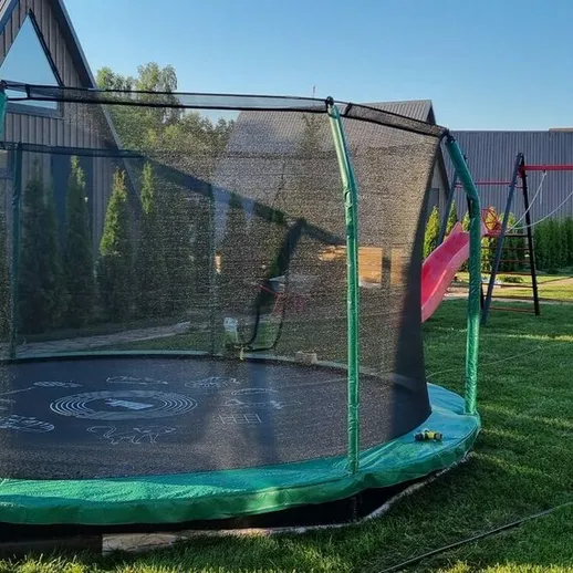 Тенистый участок с батутом и детской площадкой в загородном доме на солнечном летнем дне