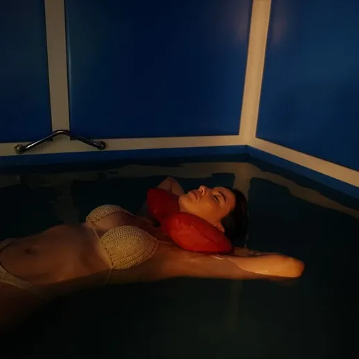 Женщина отдыхает в глубоком бассейне с приглушённым светом и вдохновляющим настроением на вечернем плавании