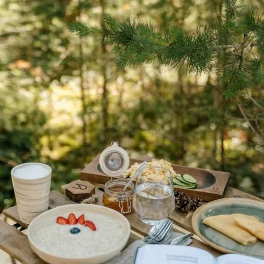 Завтрак на свежем воздухе среди природы с овсянкой и фруктами в солнечное утро