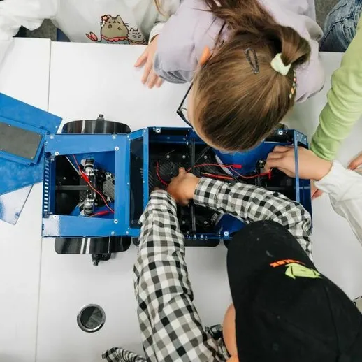 Ученики работают над сборкой робота в мастерской во время образовательного занятия в школе