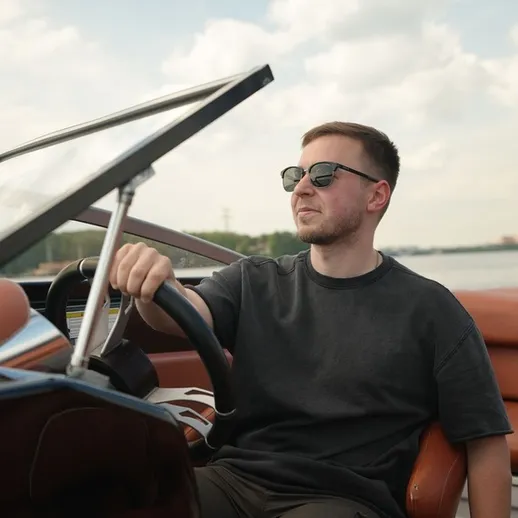 Мужчина управляет катером на реке в солнечный день, наслаждаясь свежим воздухом и свободой на воде