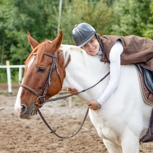 Женщина обнимает лошадь на конной базе в деревне в летний день