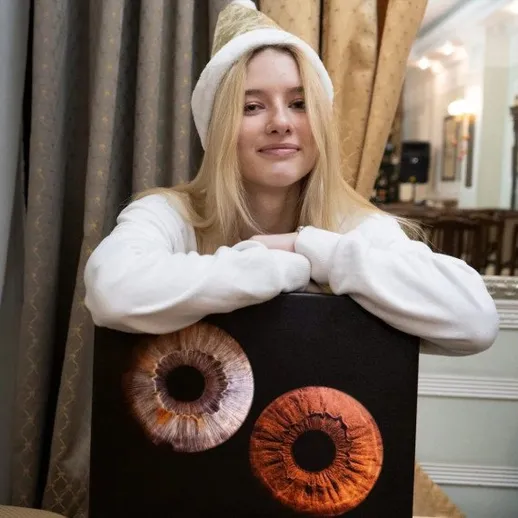 Молодая женщина позирует рядом с искусством в комнате с занавесками