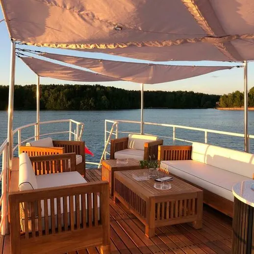 Комфортная терраса на лодке с деревянной мебелью у живописного водоёма на закате