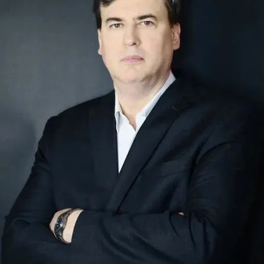 Портрет человека в строгом костюме на фоне темной стены во время профессиональной фотосессии